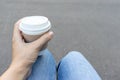 Woman sitting on a bench outdoor and holding a kraft disposadle paper cup of coffee with a white cup in hand Royalty Free Stock Photo