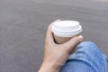 Woman sitting on a bench outdoor and holding a kraft disposadle paper cup of coffee with a white cup in hand Royalty Free Stock Photo