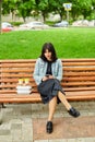 Woman sitting on the bench in the park with take away food and coffee Royalty Free Stock Photo