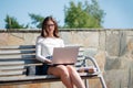 Woman sitting on bench in park and using laptop Royalty Free Stock Photo