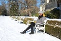 Woman sitting on bench by riding-school of Palace Hluboka during winter