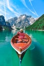 woman sitting in big brown boat at lago di braies lake in Italy