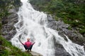 Woman sitting at the big powerful waterfall. Royalty Free Stock Photo