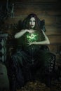 Woman sitting in a black, Gothic throne with a green light in her hands Royalty Free Stock Photo