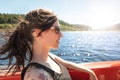 Woman sitting in a Boat, blue Lake and the Sun in the Background