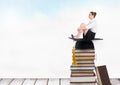 woman sitting on Books stacked by blue sky with graduation hat Royalty Free Stock Photo