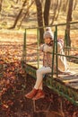 Woman sitting on a bridge in the forest on sunny autumn day Royalty Free Stock Photo