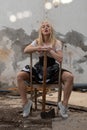 Woman sitting on a broken chair in an abandoned demolished room.
