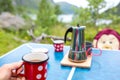 Woman, sitting on a camping chair in front of a tent, enjoying cup of coffee and amazing view in Norway Nordland, Senja island in