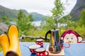 Woman, sitting on a camping chair in front of a tent, enjoying cup of coffee and amazing view in Norway Nordland, Senja island in