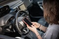 Woman sitting in a car in the driver& x27;s seat looking at a smartphone, paying for parking and navigating in the city Royalty Free Stock Photo