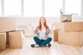 Woman sitting among cardboard boxes, housewarming