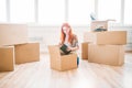 Woman sitting among cardboard boxes, housewarming