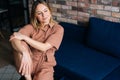 Woman sitting in a comfortable chair in dark living room, looking at the camera. Royalty Free Stock Photo