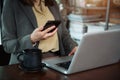 Woman sitting in a chair Hand typing on a laptop and using a smartphone to make financial transactions