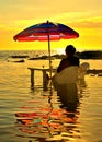 28.08.2018.woman sitting on chair immersed in the sea water, relax and drink coffee under umbrella with the background of a colorf Royalty Free Stock Photo