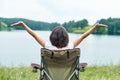Woman sitting on chair in nature near the lake. Outdoor relaxing in summer. Raising your Hands up Royalty Free Stock Photo