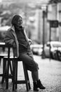 A woman sitting on a chair outside a sidewalk cafe. Black and white photo. Royalty Free Stock Photo