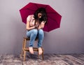 Woman sitting on the chair with smartphone and umbrella