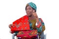 Woman sitting in a chair with traditional loincloths on her legs and on the shoulder showing her thumb while smiling