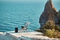 Woman sitting on chair and typing on laptop, seascape on background. Business travelling and distance work concept