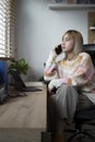 Woman sitting on comfortable chair at home office and talking on mobile phone. Royalty Free Stock Photo