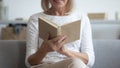 Woman sitting on couch closeup focus on hands holding book Royalty Free Stock Photo