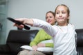 Woman sitting on couch and girl holding remote control Royalty Free Stock Photo