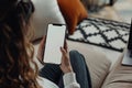 Woman sitting on couch, holding cell phone with white screen using thumb gesture Royalty Free Stock Photo