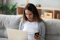 Woman using laptop and smartphone using bluetooth pairing two devices