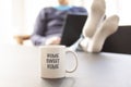 Woman sitting in a couch with a laptop computer and her feet up on a table where a mug or cup with the text HOME SWEET HOME is pla