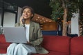 a woman is sitting on a couch with a laptop and talking on a cell phone in nice modern coworking office Royalty Free Stock Photo