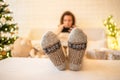 Woman sitting on couch near christmas tree. Female legs, feet in winter woolen socks putting on the table and relaxing Royalty Free Stock Photo