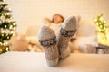 Woman sitting on couch near christmas tree. Female legs, feet in winter woolen socks putting on the table and relaxing Royalty Free Stock Photo