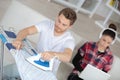 Woman sitting at couch whil man ironing