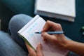 Woman sitting on couch and writing diary to do list for today closeup