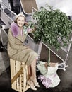 Woman sitting on a crate of oranges next to a plane and citrus tree Royalty Free Stock Photo