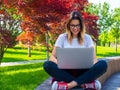 Woman sitting cross-legged with laptop outdoors. Online education concept Royalty Free Stock Photo