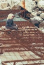 Woman sitting on damaged concrete and steel