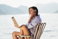 Woman sitting on deck chair by the sea using tablet on a sunny day Royalty Free Stock Photo