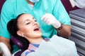 Woman sitting in dental chair while doctor examining her teeth