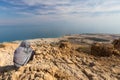 Woman sitting desert mountain edge above sea.