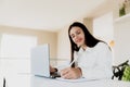 Woman sitting at desk, reading from laptop, writing notes at her notebook Royalty Free Stock Photo