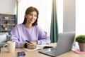 Woman sitting at desk, using computer writing in notebook Royalty Free Stock Photo