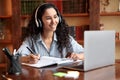 Woman sitting at desk, using laptop and writing in notebook Royalty Free Stock Photo