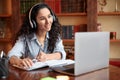 Woman sitting at desk, using laptop and writing in notebook Royalty Free Stock Photo