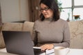 Woman sitting at desk, working on computer at home. Pleasant attractive smiling lady looking at laptop screen, shopping, chatting Royalty Free Stock Photo