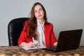 A woman sitting at a desk working with a laptop and notepad