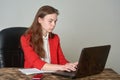A woman sitting at a desk working with a laptop and notepad
