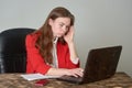 A woman sitting at a desk working with a laptop and notepad